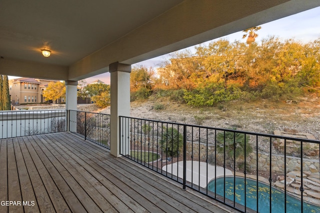 deck at dusk with a fenced in pool