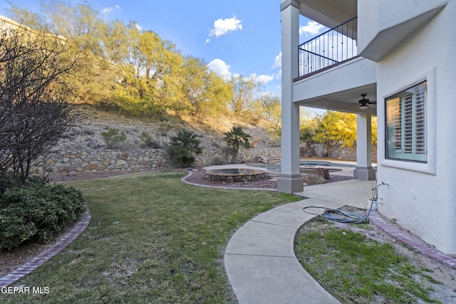 view of yard featuring ceiling fan, a swimming pool with hot tub, a balcony, and a patio area