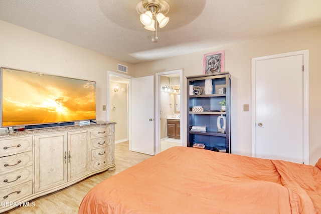 bedroom featuring ensuite bath, ceiling fan, a textured ceiling, and light wood-type flooring