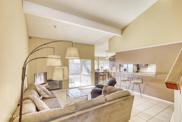 tiled living room featuring vaulted ceiling with beams, ceiling fan, and a textured ceiling