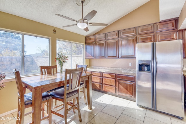 kitchen featuring light stone countertops, a textured ceiling, stainless steel fridge with ice dispenser, lofted ceiling, and light tile patterned flooring