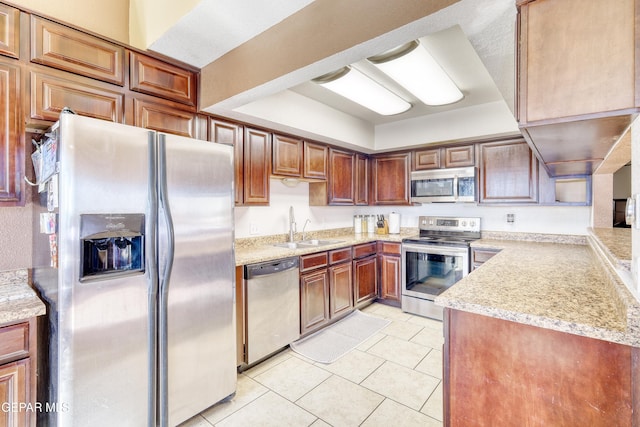 kitchen featuring kitchen peninsula, appliances with stainless steel finishes, light stone counters, sink, and light tile patterned floors