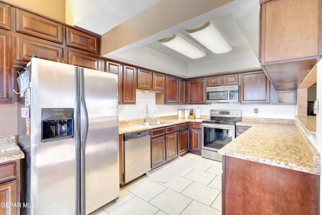 kitchen with light stone countertops, sink, light tile patterned floors, and stainless steel appliances