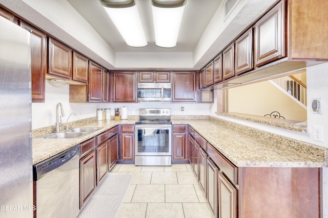 kitchen with light stone countertops, light tile patterned floors, stainless steel appliances, and sink