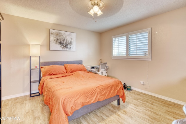 bedroom with ceiling fan, a textured ceiling, and light hardwood / wood-style flooring