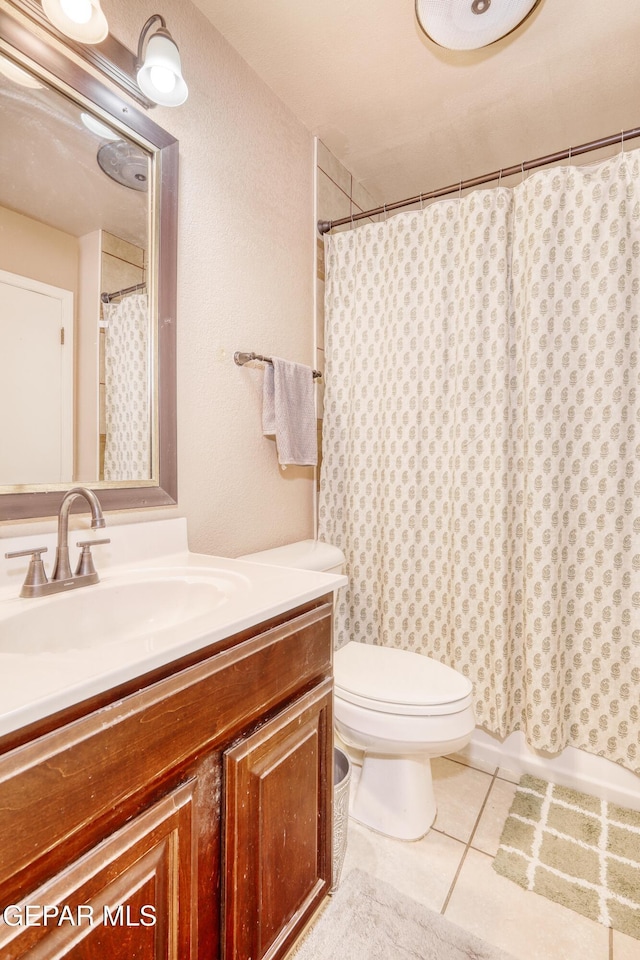 bathroom featuring tile patterned flooring, vanity, curtained shower, and toilet