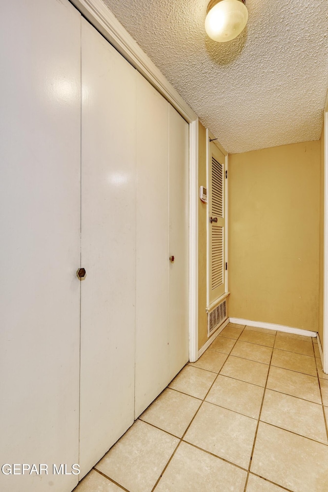 corridor featuring tile patterned flooring and a textured ceiling