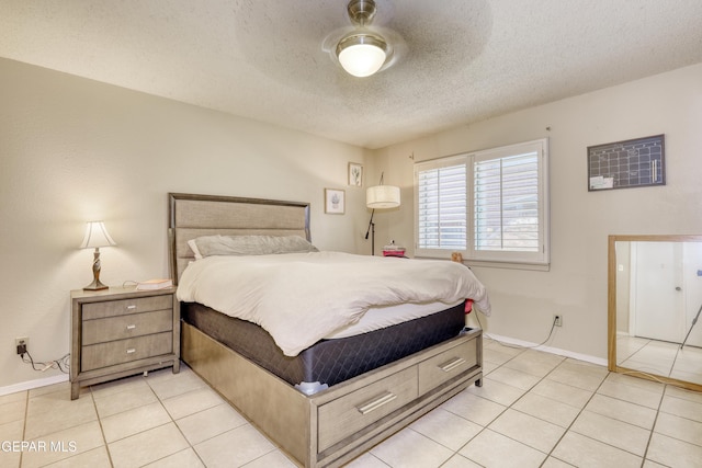 bedroom featuring ceiling fan, light tile patterned floors, and a textured ceiling