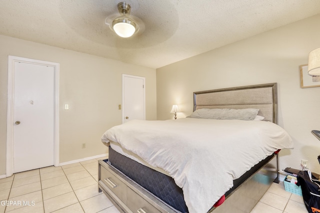 bedroom featuring ceiling fan, light tile patterned floors, and a textured ceiling