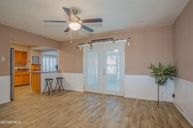 interior space featuring french doors, a textured ceiling, light hardwood / wood-style floors, and ceiling fan