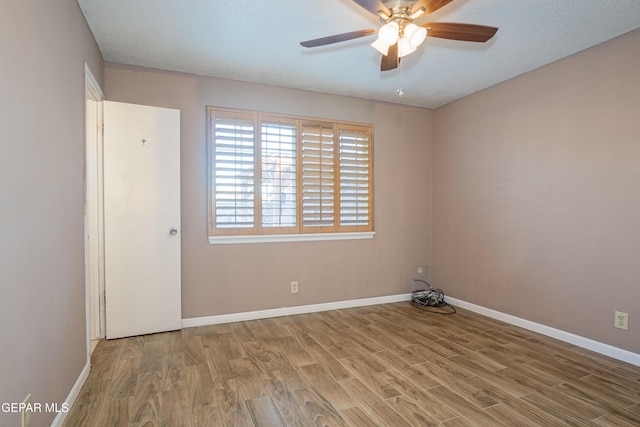 empty room featuring ceiling fan, light wood-type flooring, and a textured ceiling