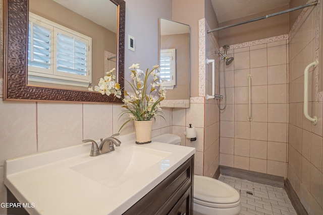 bathroom with tiled shower, vanity, tile walls, and toilet