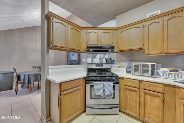 kitchen featuring gas range, a textured ceiling, ventilation hood, and light tile patterned floors