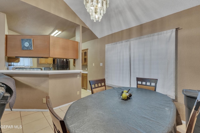 tiled dining space featuring a chandelier and lofted ceiling