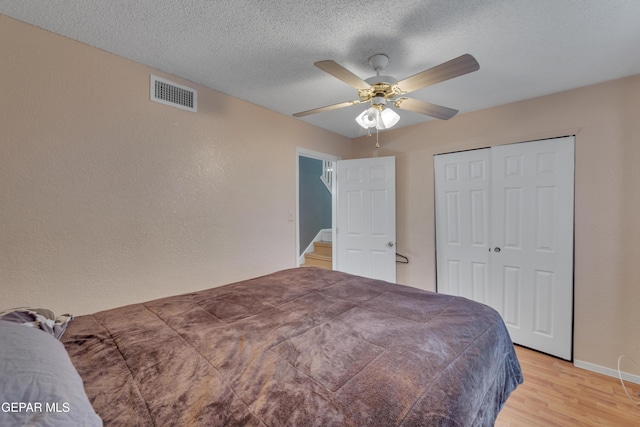 bedroom featuring a textured ceiling, a closet, hardwood / wood-style flooring, and ceiling fan