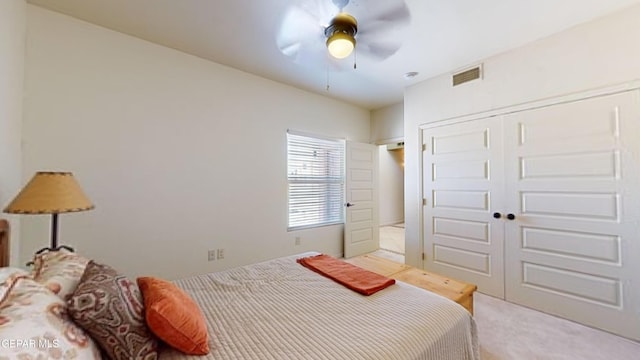 bedroom with ceiling fan, light carpet, and a closet