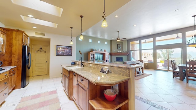 kitchen with a skylight, ceiling fan, sink, hanging light fixtures, and a spacious island