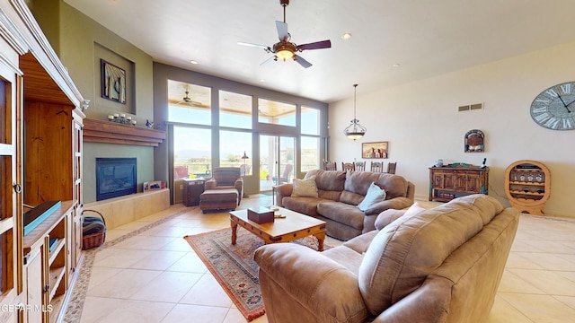 living room featuring a tile fireplace, light tile patterned floors, and a high ceiling