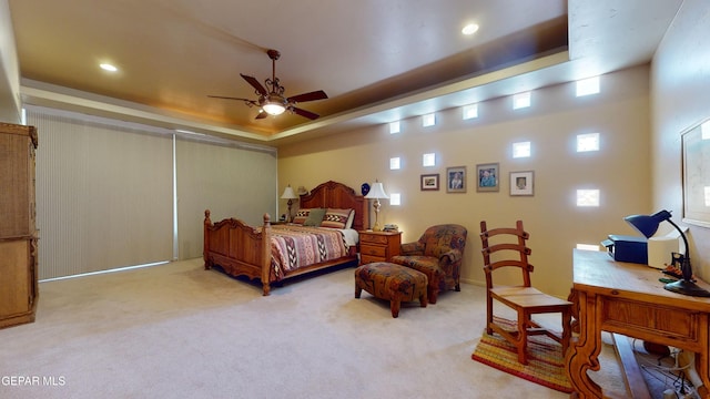 carpeted bedroom featuring a tray ceiling and ceiling fan