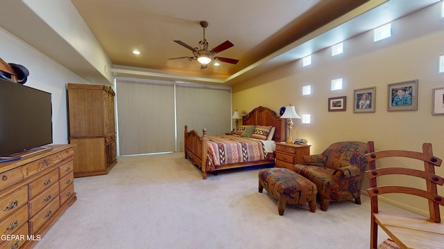 carpeted bedroom with a raised ceiling and ceiling fan