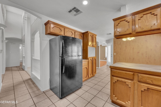 kitchen featuring light tile patterned floors, black fridge, and tile countertops