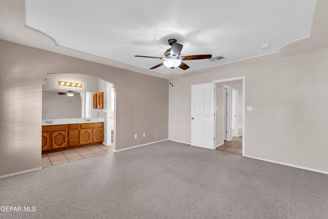 unfurnished bedroom featuring light tile patterned floors, ceiling fan, and ensuite bathroom