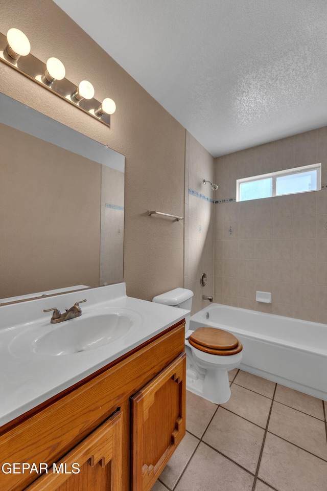 full bathroom featuring toilet, tiled shower / bath, tile patterned flooring, a textured ceiling, and vanity