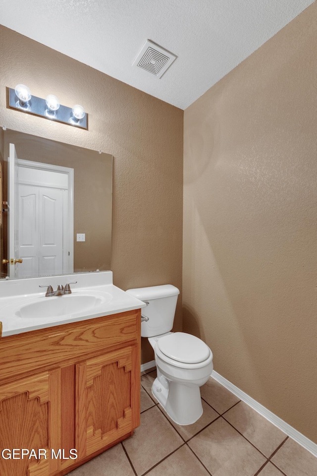 bathroom featuring a textured ceiling, toilet, vanity, and tile patterned flooring