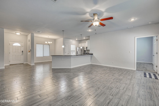 unfurnished living room with hardwood / wood-style floors and ceiling fan with notable chandelier