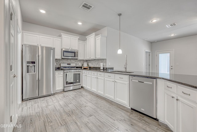 kitchen with sink, light hardwood / wood-style flooring, appliances with stainless steel finishes, decorative light fixtures, and white cabinetry