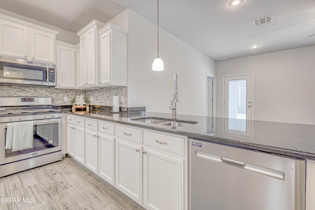 kitchen with appliances with stainless steel finishes, backsplash, sink, light hardwood / wood-style floors, and white cabinetry