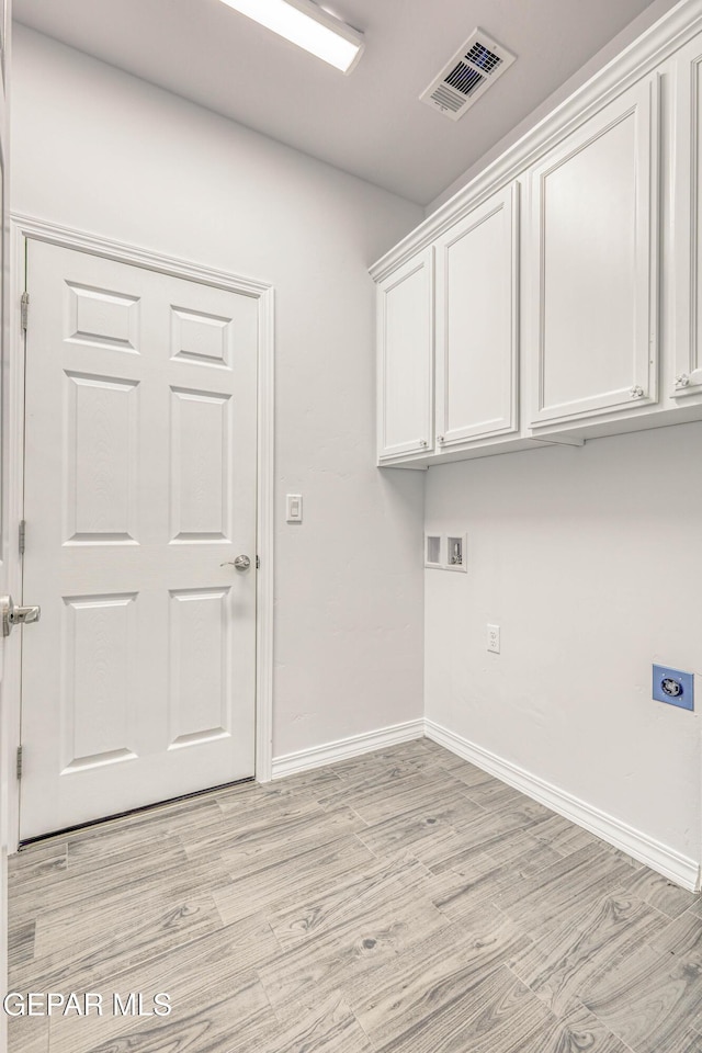 clothes washing area with hookup for an electric dryer, washer hookup, cabinets, and light hardwood / wood-style flooring