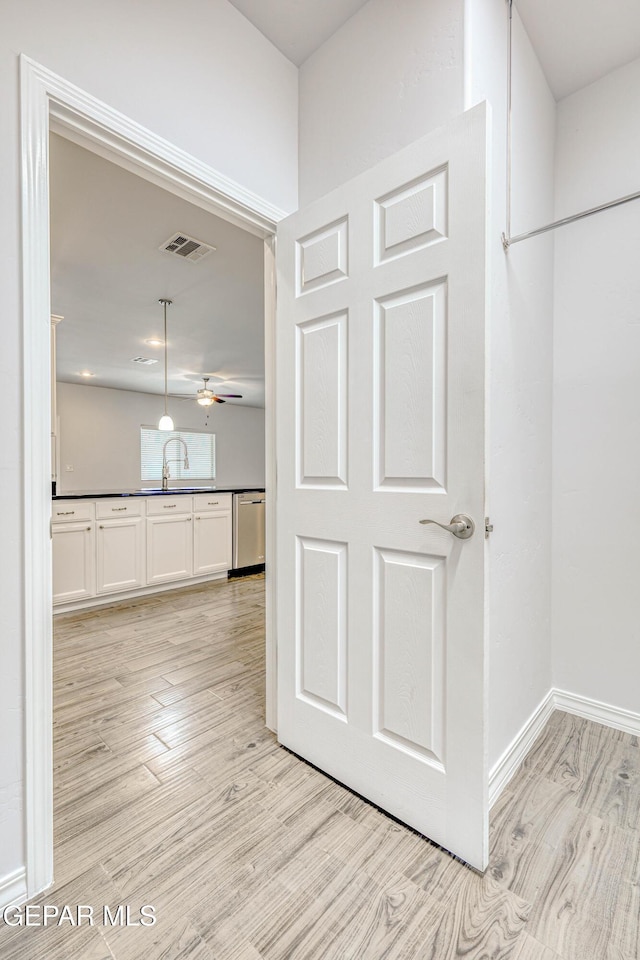 hall with light hardwood / wood-style floors and sink