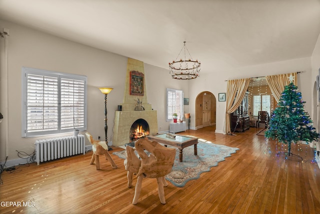 living room featuring radiator, a fireplace, wood-type flooring, and pool table