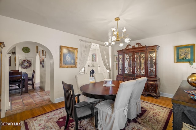 1117 Kerbey Ave, El Paso, TX 79902 - dining area featuring arched walkways, a chandelier, and wood finished floors