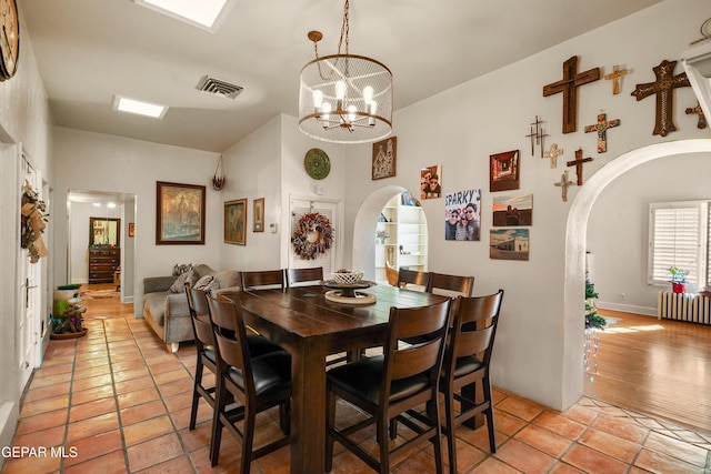 dining area featuring an inviting chandelier, light hardwood / wood-style flooring, and radiator