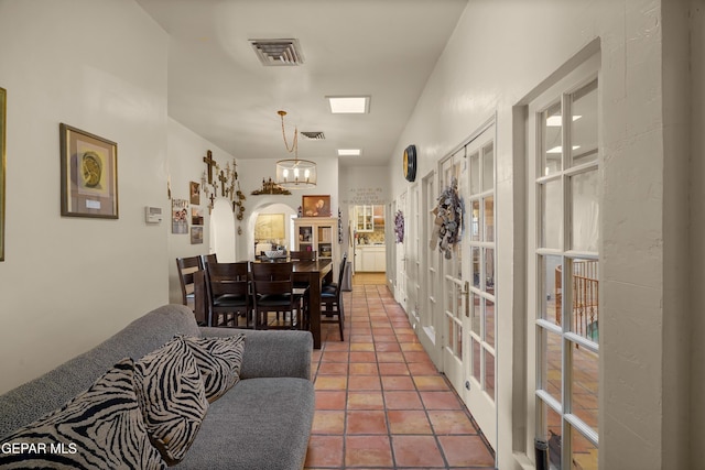 dining space with french doors, tile patterned floors, and a notable chandelier