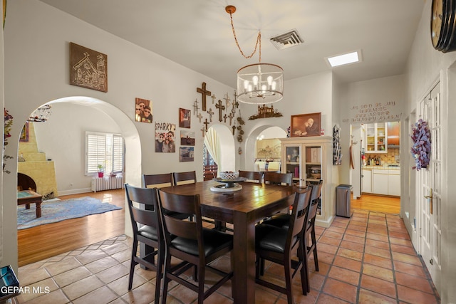 dining area with a notable chandelier, light hardwood / wood-style floors, and radiator heating unit