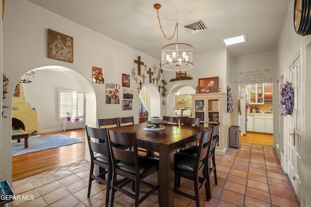 1117 Kerbey Ave, El Paso, TX 79902 - dining space with radiator heating unit, arched walkways, a chandelier, and light tile patterned floors