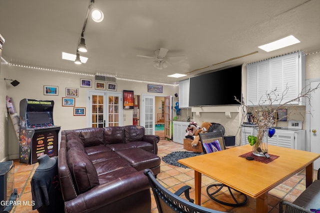 tiled living room featuring ceiling fan, track lighting, and french doors