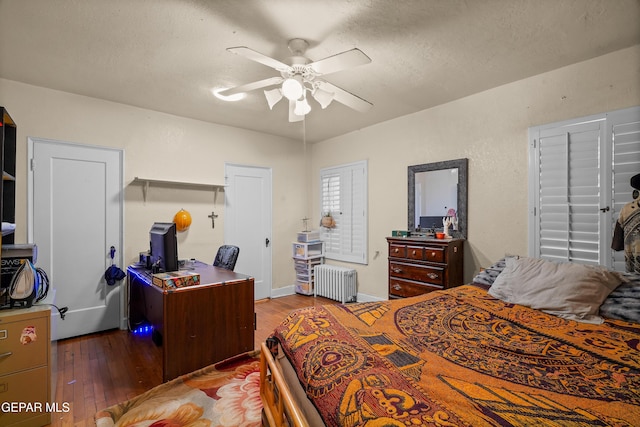 bedroom featuring radiator, ceiling fan, dark wood-type flooring, and a textured ceiling