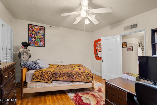 bedroom with ceiling fan, light hardwood / wood-style flooring, and a textured ceiling