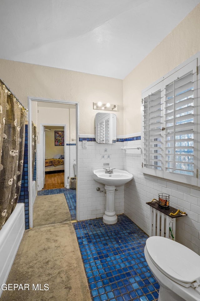 bathroom featuring toilet, tile walls, and shower / tub combo