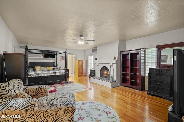 bedroom with ceiling fan, a textured ceiling, and light hardwood / wood-style flooring