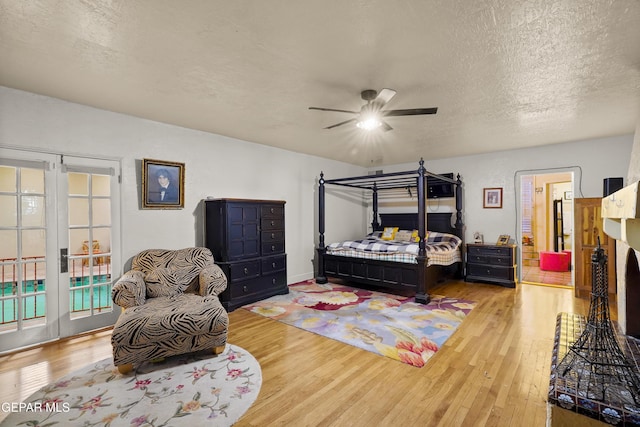 bedroom with french doors, a textured ceiling, access to outside, ceiling fan, and wood-type flooring