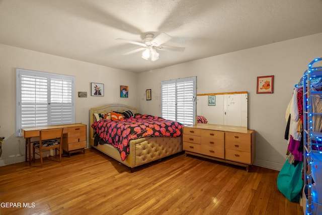 bedroom with multiple windows, ceiling fan, light hardwood / wood-style floors, and a textured ceiling