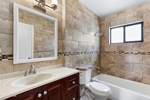 full bathroom featuring tiled shower / bath combo, toilet, tile walls, and vanity