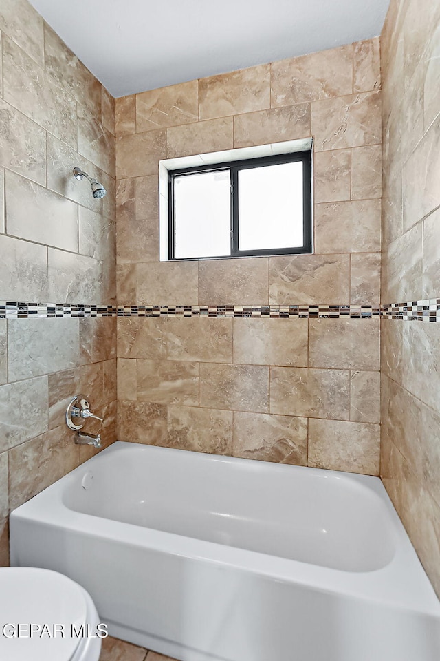 bathroom with tiled shower / bath combo and toilet