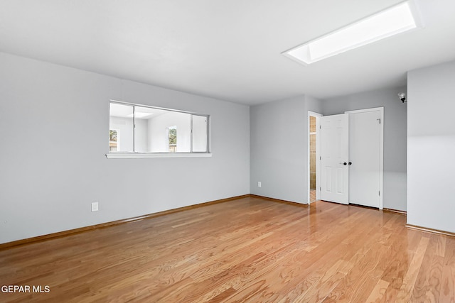 unfurnished room with light wood-type flooring and a skylight