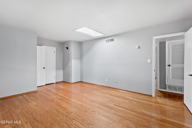 empty room featuring light hardwood / wood-style floors and a skylight